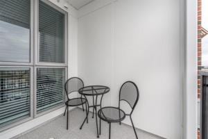 three chairs and a table in a room with windows at Modern Old Town Suite With Private Balcony in Victoria +1 photo