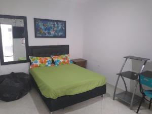 a bedroom with a bed with a green comforter and a table at usoinmobiliario in Medellín