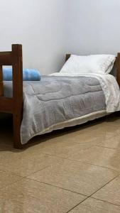 a bed with a gray blanket and a white pillow at Apto 27 Flamingo in Pato Branco