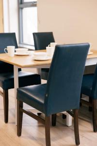 een houten tafel met vier stoelen en een tafel met kopjes erop bij River Walk Apartments in Derry Londonderry