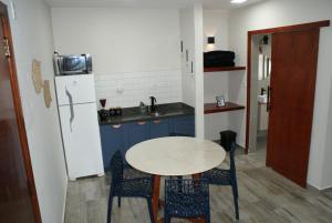 a small kitchen with a table and a refrigerator at Flat Sirena - São Vicente in São Vicente