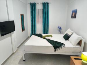 a bedroom with a white bed with green curtains at Plateau Bedroom & Chambre - Praia Center 1 in Praia