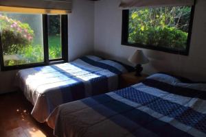 two beds in a room with two windows at Hermoso Jardín con casa de campo en Avandaro in Avándaro