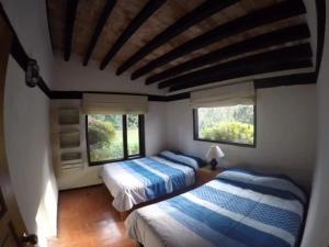 a bedroom with two beds and two windows at Hermoso Jardín con casa de campo en Avandaro in Avándaro