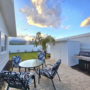 patio con sedie, tavolo e grill di Pasture Views Cottage a Riwaka