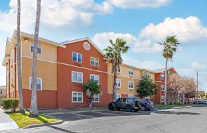 a building with palm trees and a car parked in a parking lot at Extended Stay America Suites - Corpus Christi - Staples in Corpus Christi