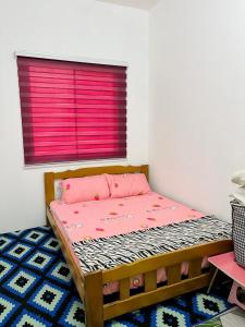 Cama en habitación con ventana rosa en Homestay Keboon Rantau Panjang, en Rantau Panjang