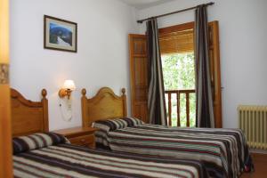 1 Schlafzimmer mit 2 Betten und einem Fenster mit einer Tür in der Unterkunft Apartamentos Rurales Poqueira in Capileira + 86 Fotos