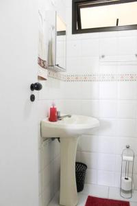 ein weißes Badezimmer mit Waschbecken und Spiegel in der Unterkunft Espaço entre Pizza & Café in Pindamonhangaba