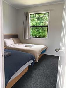 two beds in a small room with a window at 5 Bedroom House, 7 Salisbury Road, Rotorua in Rotorua