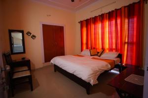 a bedroom with a bed with red curtains at Kainchi Premium Homestay 4BHk in Bhowāli