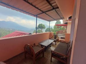 a balcony with a table and chairs and a view at Kainchi Premium Homestay 4BHk in Bhowāli
