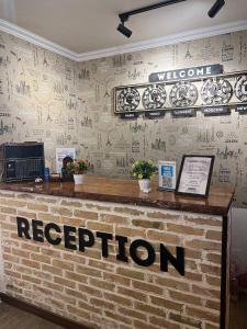 a reception desk with a welcome sign on a brick wall at Usman in Samarkand