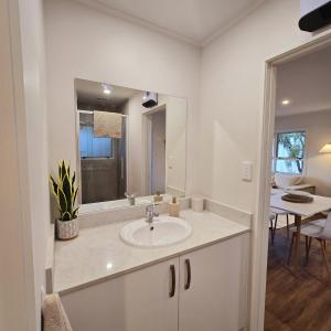 bagno bianco con lavandino e specchio di Pasture Views Cottage a Riwaka