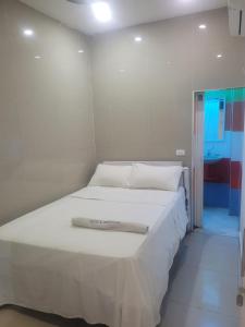 - un lit blanc avec une serviette dans la chambre dans l'établissement Hotel Calderon, à Valledupar