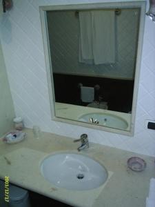 ein Bad mit einem Waschbecken und einem Spiegel in der Unterkunft Hotel Taloro in Gavoi