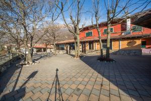 cortile in mattoni con alberi di fronte a un edificio di Hotel La Solitaria a Carlazzo