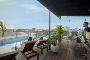 two people sitting in chairs on a deck with a pool at Onederz Siem Reap in Siem Reap