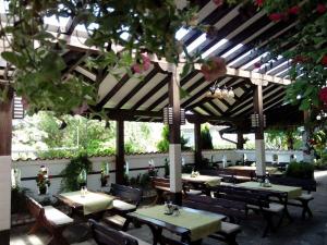 a restaurant with tables and chairs under a wooden umbrella at Guest House Dan Kolov in Syennik