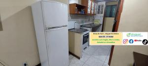 a white refrigerator in a kitchen with a sign on it at Arraial do Cabo - Brisas do Farol - Aluguel Econômico in Arraial do Cabo