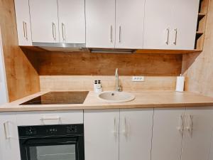 a kitchen with white cabinets and a sink at AGOLL Centru - self checkin in Reşiţa +36 photos