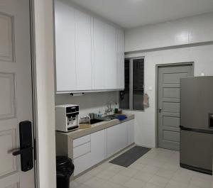 uma cozinha com armários brancos e uma geladeira em Coziness Suite with high speed WiFi dan Netflix em Sitiawan