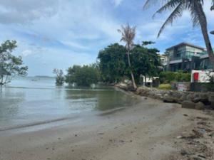 a beach with water and palm trees and houses at Luxury 4 Bedroom Beach House in Ban Saiyuan (1)