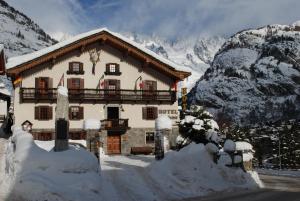 un bâtiment recouvert de neige devant une montagne dans l'établissement Hotel Des Glaciers, à Courmayeur