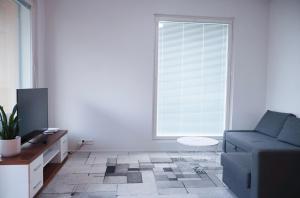 a living room with a blue couch and a window at Modern 2-Bedroom Apartment with Sauna, Forest View & Parking in Espoo