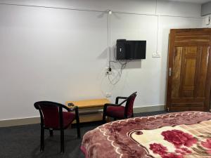 a room with a bed and two chairs and a table at Amaze PY Homestay in Tawang