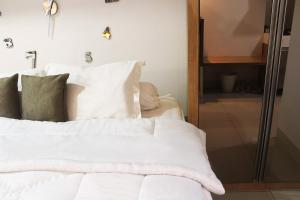 a bed with white sheets and pillows in a room at 7 min to ICE 1BR with Wifi, Netflix, AC, Kitchen, TV, Swimming Pool, Gym, Free Parking in Dadap