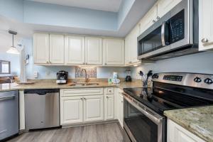 a kitchen with white cabinets and stainless steel appliances at Bluewater Vacation Rentals in Orange Beach