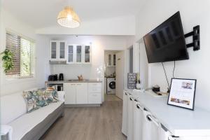 a living room with a white couch and a flat screen tv at Zen Escape Guest House " Location 2" - Zen Garden Tiny Home, Nooky Studio, Chillax Rest in Brisbane