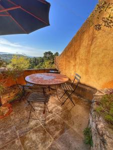 a table and chairs on a patio with an umbrella at Les 3 Terrasses in Roussillon
