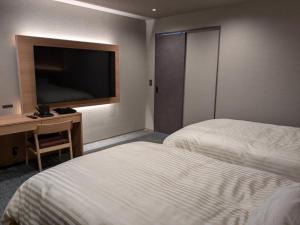 a hotel room with two beds and a flat screen tv at Onyado Tsutaya in Kiso