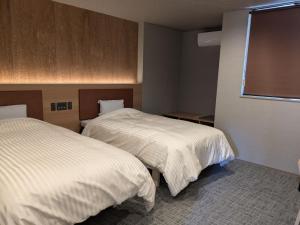 a hotel room with two beds and a window at Onyado Tsutaya in Kiso