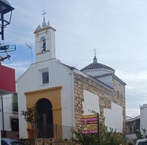 a church with a steeple and a clock tower at Loft Plaza in Hornachuelos