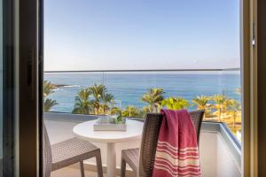 a table and chairs with a view of the ocean at Queens Bay Hotel in Paphos