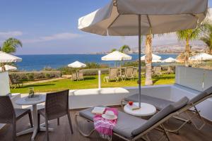 a patio with a table and chairs and an umbrella at Queens Bay Hotel in Paphos