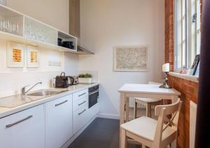 een kleine keuken met een wastafel en een tafel bij Rotheram (Suite) at Bicester Heritage in Bicester
