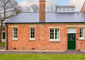 een rood bakstenen huis met een groene deur bij Rotheram (Suite) at Bicester Heritage in Bicester