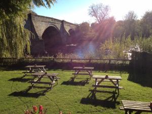 a group of picnic tables in the grass near a bridge at The Bull Inn West Tanfield in Ripon