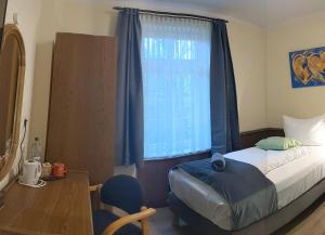 a bedroom with a bed and a window with blue curtains at Pension Celia in Wismar