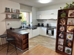 a kitchen with white cabinets and a counter with stools at Johnyho Bydlení Velikovská 10, Zlín-Štípa in Zlín