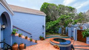 una casa azul con un patio con una fuente en Milkwood Beach Villa, en Wilderness