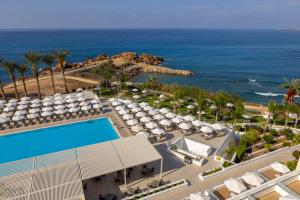 an aerial view of a resort with a swimming pool and the ocean at Queens Bay Hotel in Paphos