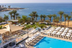 an aerial view of a resort with a pool and the ocean at Queens Bay Hotel in Paphos
