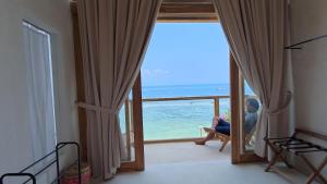Ein Mann, der in einem Zimmer mit Meerblick sitzt in der Unterkunft Noosa Dive Resort in Nusa Penida