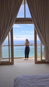Eine Frau steht in einem Fenster mit Blick auf den Ozean in der Unterkunft Noosa Dive Resort in Nusa Penida