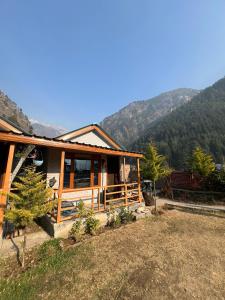 una casa in legno con montagne sullo sfondo di Lee Garden Himalayan Wooden Cottages a Kasol